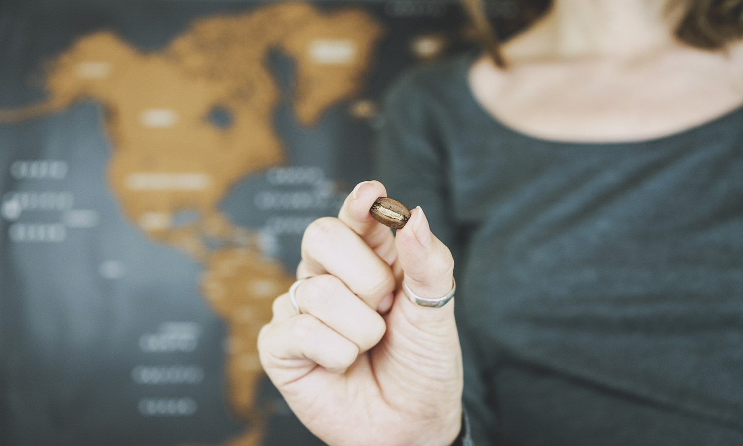 Mulher segurando grão de café e mapa ao fundo